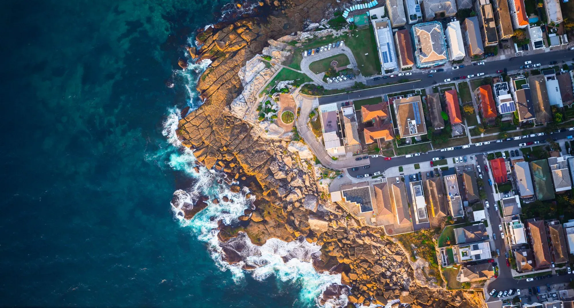 Aerial view of a rocky ocean headland and seaside streets, for Laura Nocera's LN Property Buyers guide to what a Sydney buyers agent does